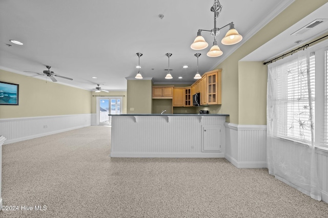 kitchen with a kitchen bar, ceiling fan with notable chandelier, light colored carpet, crown molding, and decorative light fixtures