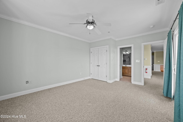 unfurnished bedroom with carpet, ensuite bathroom, ornamental molding, ceiling fan, and a closet