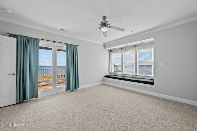 carpeted empty room with ceiling fan, a water view, and ornamental molding