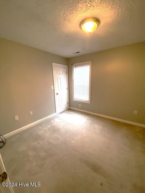 carpeted empty room featuring a textured ceiling