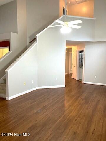 unfurnished living room with ceiling fan, dark hardwood / wood-style flooring, and high vaulted ceiling