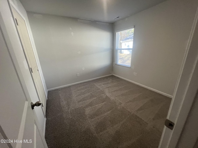 unfurnished room featuring dark carpet