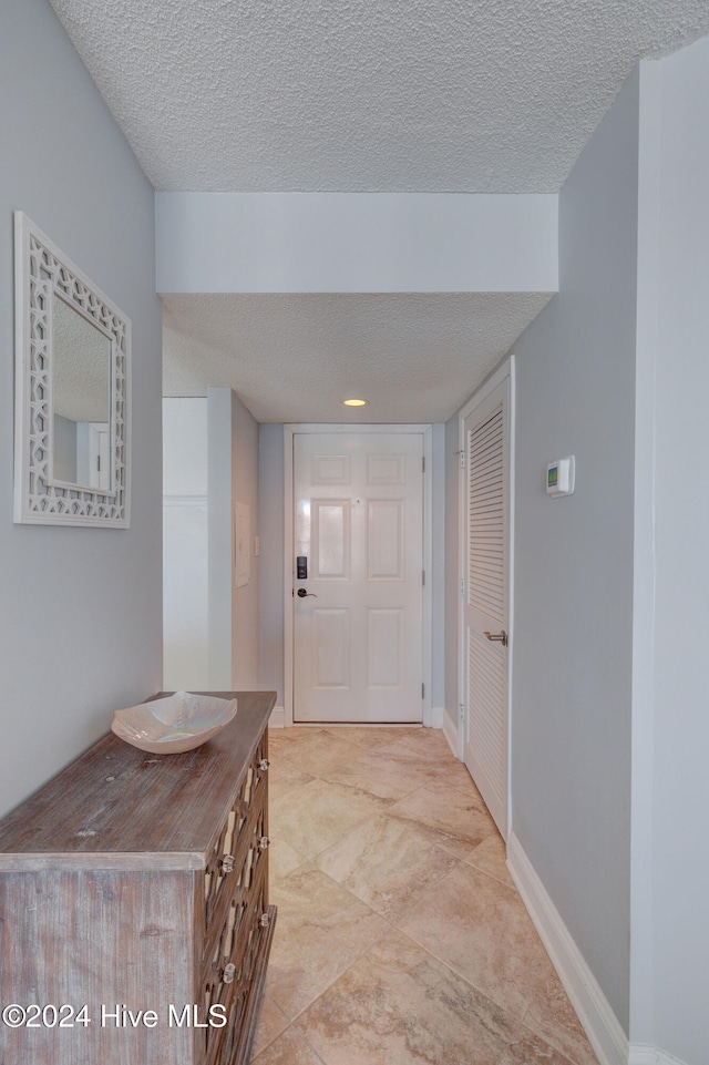 hallway with light tile patterned floors and a textured ceiling