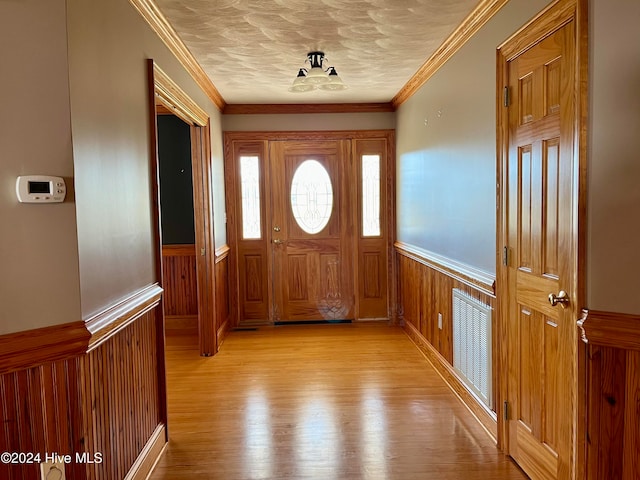 doorway to outside featuring crown molding, a textured ceiling, and light wood-type flooring