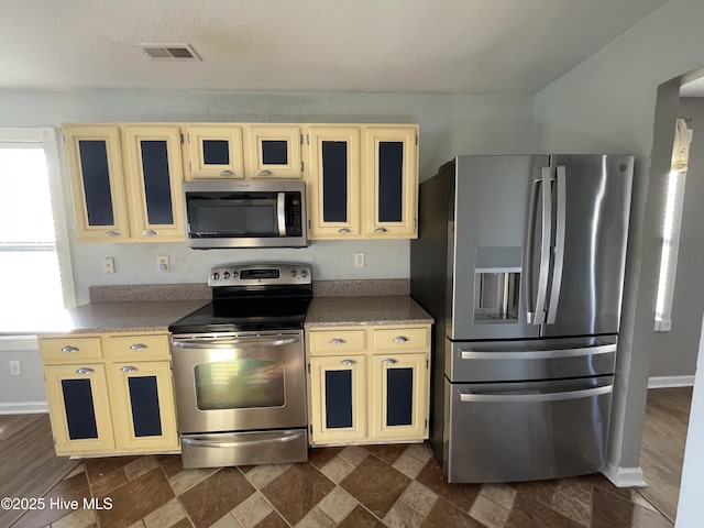 kitchen featuring appliances with stainless steel finishes, cream cabinetry, and a textured ceiling