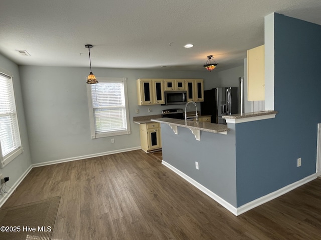 kitchen featuring appliances with stainless steel finishes, dark wood-type flooring, decorative light fixtures, a breakfast bar, and kitchen peninsula