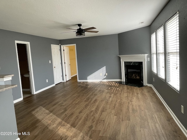 unfurnished living room with a textured ceiling, ceiling fan, dark hardwood / wood-style floors, and a fireplace