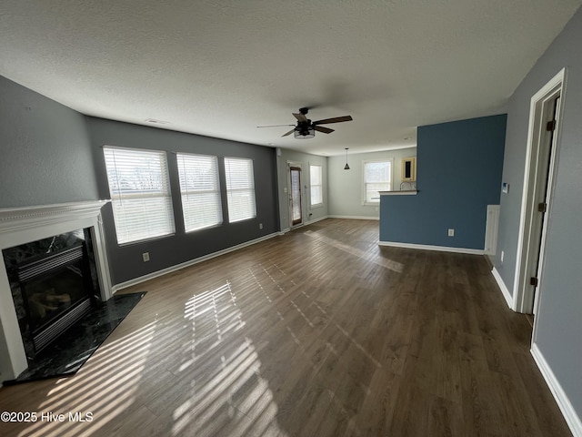 unfurnished living room featuring a textured ceiling, a high end fireplace, dark hardwood / wood-style floors, and ceiling fan