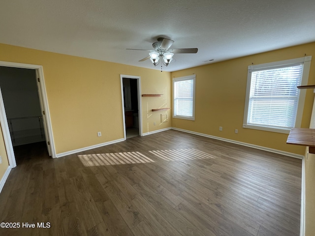 unfurnished bedroom with ceiling fan, dark hardwood / wood-style floors, and a walk in closet