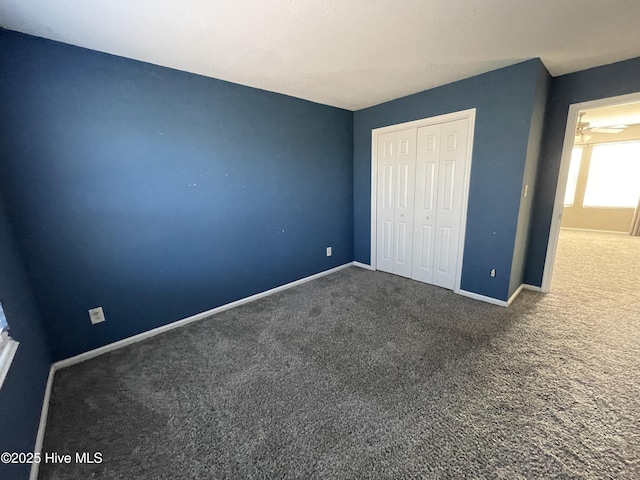 unfurnished bedroom with a closet and dark colored carpet