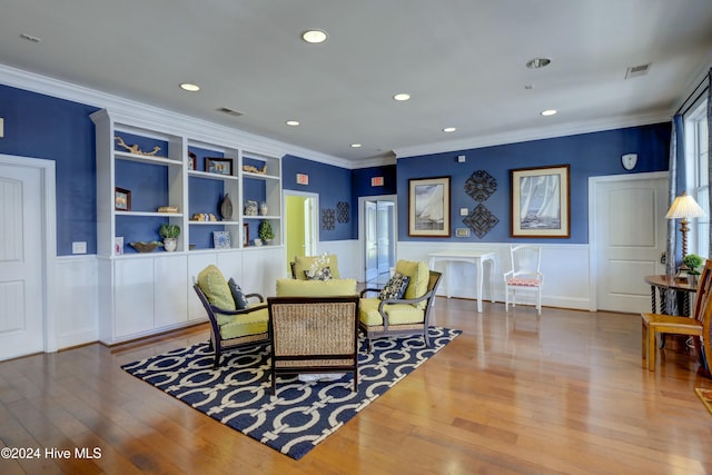 sitting room featuring hardwood / wood-style flooring, built in features, and crown molding