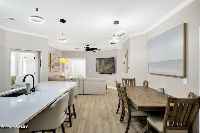 dining area featuring ceiling fan, light hardwood / wood-style flooring, ornamental molding, and sink