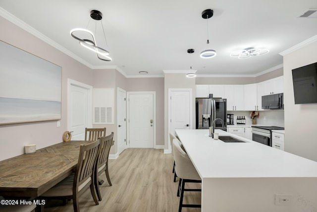 kitchen featuring pendant lighting, sink, stainless steel fridge with ice dispenser, ornamental molding, and white cabinetry