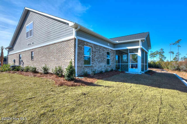 rear view of house featuring a sunroom and a yard