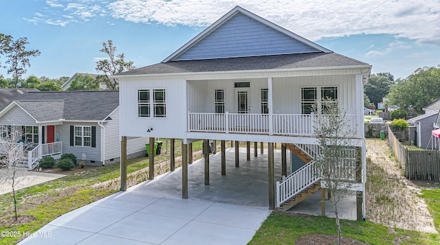 117 NW 17th St, Oak Island, NC 28465 - view of front of home featuring a carport, driveway, covered porch, roof with shingles, and stairs