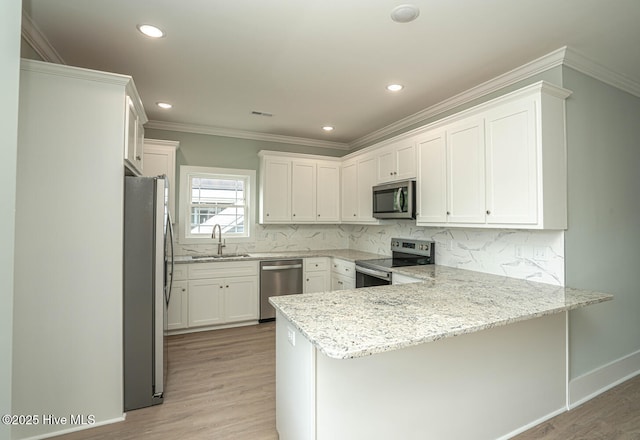 117 NW 17th St, Oak Island, NC 28465 - kitchen featuring stainless steel appliances, a peninsula, a sink, ornamental molding, and light wood finished floors