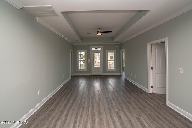 empty room featuring a raised ceiling, ceiling fan, crown molding, and dark wood-type flooring