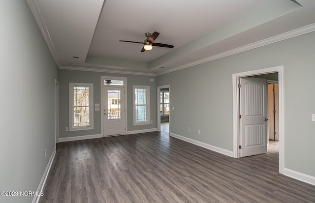 empty room featuring a raised ceiling, ceiling fan, dark wood-type flooring, and ornamental molding