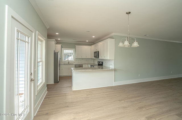 117 NW 17th St, Oak Island, NC 28465 - kitchen featuring appliances with stainless steel finishes, a sink, crown molding, open floor plan, and a chandelier