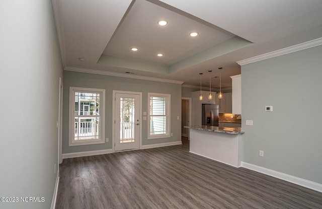 unfurnished living room with ornamental molding, dark hardwood / wood-style floors, and a tray ceiling