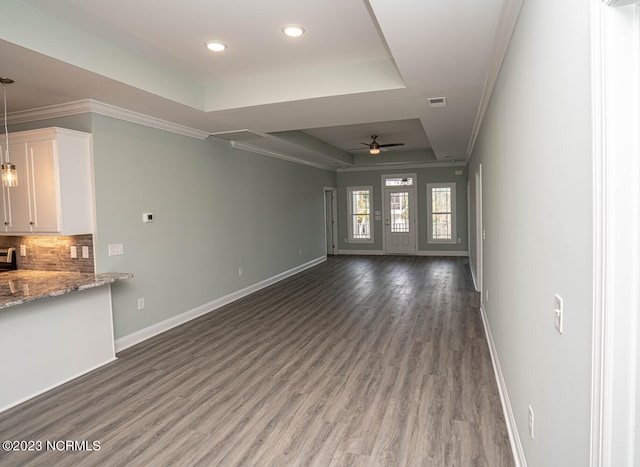 unfurnished living room with hardwood / wood-style flooring, a raised ceiling, ceiling fan, and ornamental molding