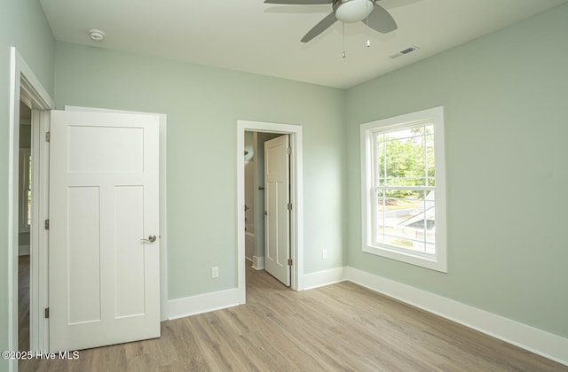 117 NW 17th St, Oak Island, NC 28465 - unfurnished bedroom featuring baseboards, light wood finished floors, ensuite bath, and a ceiling fan