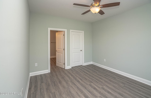 unfurnished bedroom featuring ceiling fan, a closet, and dark wood-type flooring