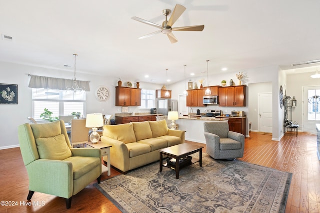 living room with dark hardwood / wood-style flooring, ceiling fan with notable chandelier, and sink