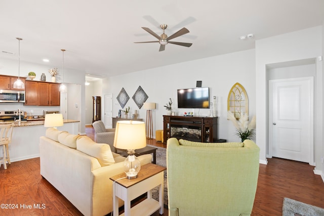 living room featuring ceiling fan and dark wood-type flooring