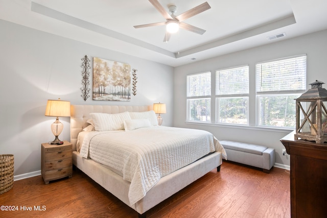 bedroom featuring ceiling fan, a raised ceiling, and dark wood-type flooring