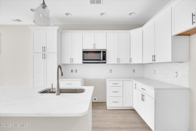 822 Kenneth Ave Unit 1, Carolina Beach, NC 28428 - kitchen with stainless steel microwave, light stone countertops, light wood-style flooring, decorative backsplash, and recessed lighting