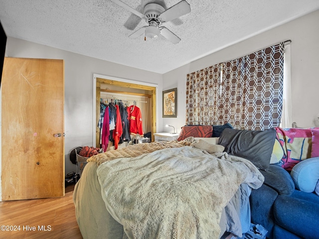 bedroom with hardwood / wood-style floors, a textured ceiling, a closet, and ceiling fan