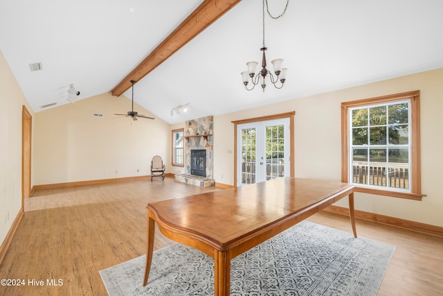 interior space featuring vaulted ceiling with beams, a wealth of natural light, a stone fireplace, and light wood-type flooring