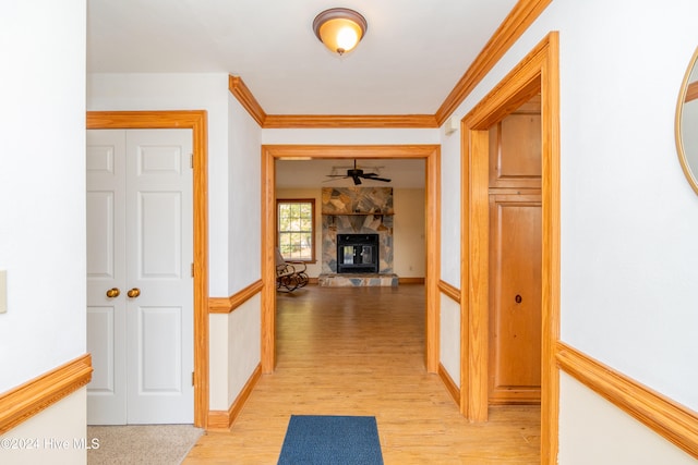 corridor with light hardwood / wood-style flooring and ornamental molding