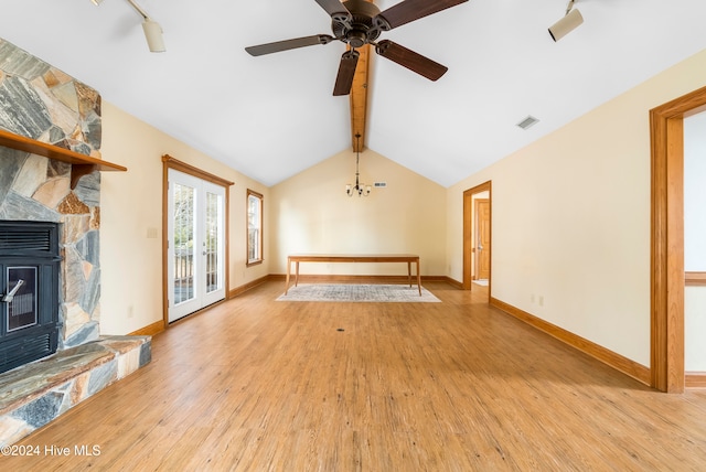 unfurnished living room featuring track lighting, french doors, lofted ceiling with beams, ceiling fan with notable chandelier, and light hardwood / wood-style floors