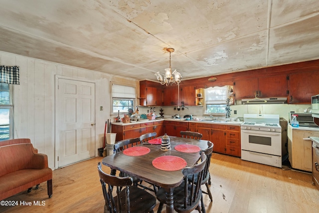 dining space featuring wooden walls, light hardwood / wood-style flooring, a chandelier, and sink