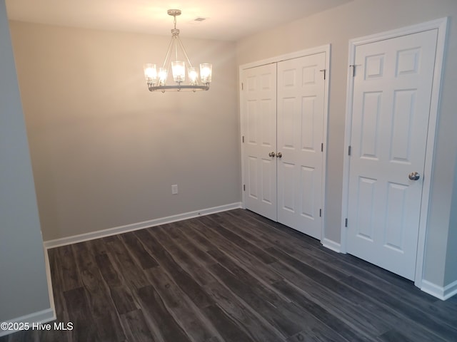 spare room with dark hardwood / wood-style floors and a notable chandelier