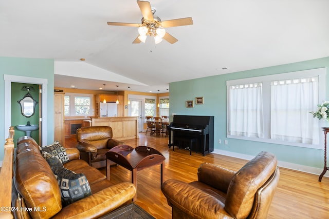 living room featuring light hardwood / wood-style flooring, vaulted ceiling, and ceiling fan