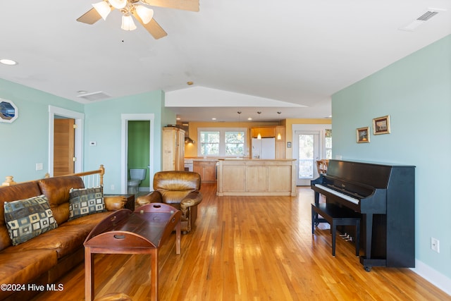 living room featuring ceiling fan, lofted ceiling, and light hardwood / wood-style flooring