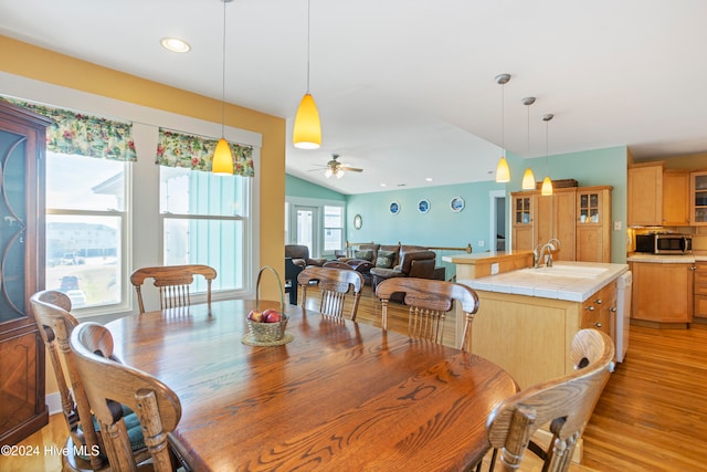 dining area featuring ceiling fan, light hardwood / wood-style flooring, lofted ceiling, and sink