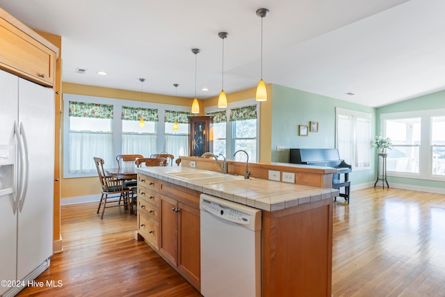 kitchen with white appliances, sink, pendant lighting, light hardwood / wood-style flooring, and tile counters