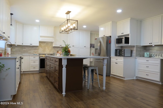 kitchen featuring a center island, dark hardwood / wood-style flooring, backsplash, white cabinets, and appliances with stainless steel finishes