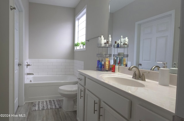 bathroom with a tub to relax in, toilet, vanity, and hardwood / wood-style flooring