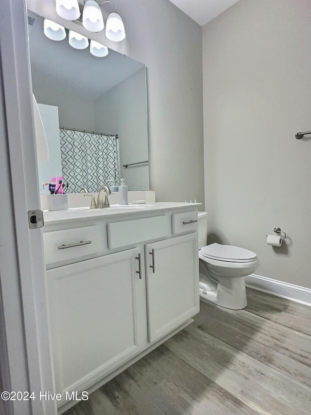 bathroom featuring hardwood / wood-style floors, vanity, toilet, and walk in shower