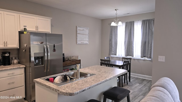 kitchen featuring a kitchen island, stainless steel fridge, a chandelier, white cabinets, and hardwood / wood-style flooring