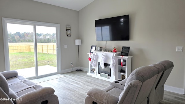 living room featuring light hardwood / wood-style floors, vaulted ceiling, and plenty of natural light