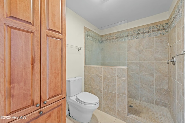 bathroom featuring toilet, tile patterned flooring, and tiled shower