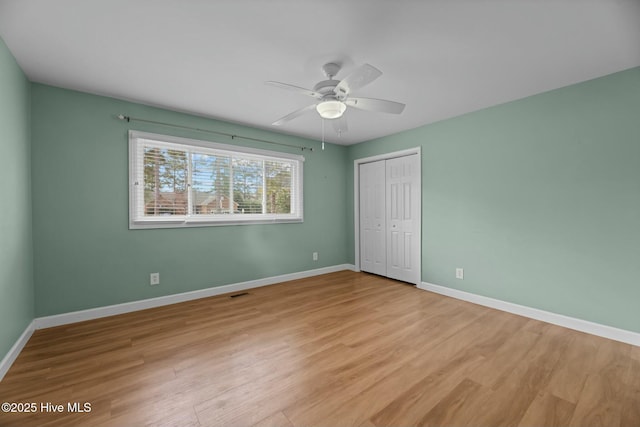 unfurnished bedroom featuring ceiling fan, light wood-type flooring, and a closet