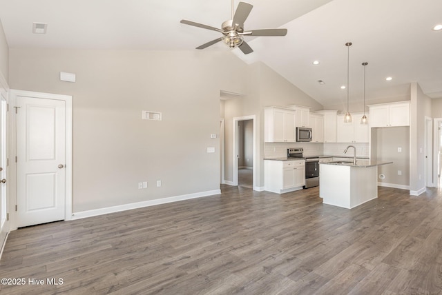 kitchen featuring a center island with sink, white cabinets, high vaulted ceiling, and decorative light fixtures