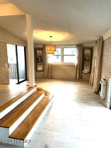 interior space with a fireplace, light wood-type flooring, heating unit, and brick wall